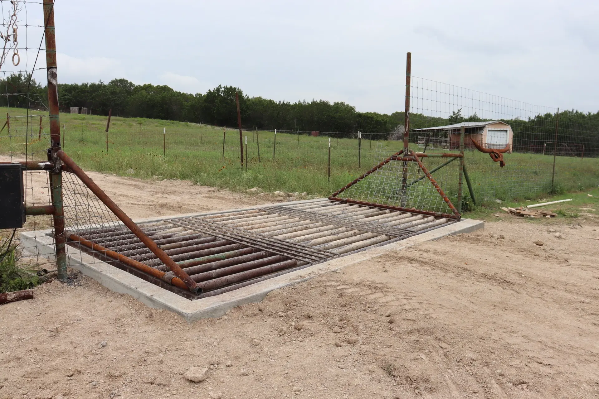 Ranch fencing and cattle guard work across rolling Burnet County pasture